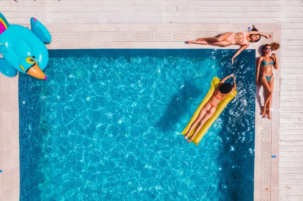 Amis en maillot de bain qui bronzent dans le transat dans une piscine — Photo