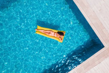 Yüzme havuzunda bronzlaşan mayo giymiş kız.
