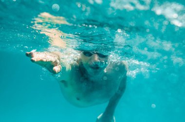 Gözlüklü sportif adam denizde hızlı yüzer.