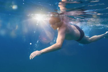 Gözlüklü sportif adam denizde hızlı yüzer.