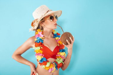 Woman with swimsuit and hat refreshing with a coconut