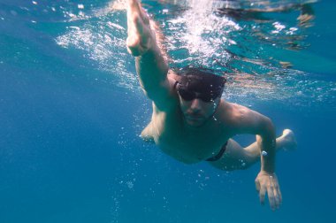 Gözlüklü sportif adam denizde hızlı yüzer.