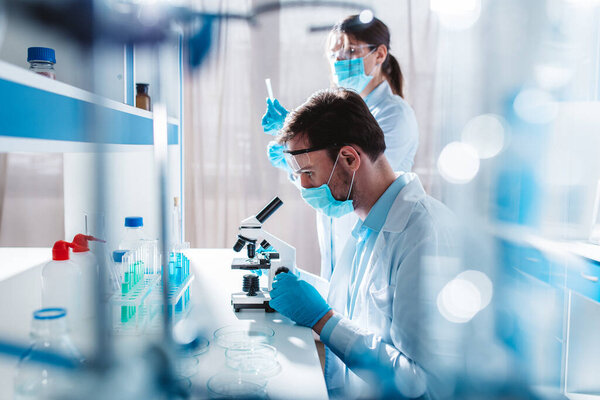 Исследователь изучает новые методы лечения ковида-19 под микроскопом