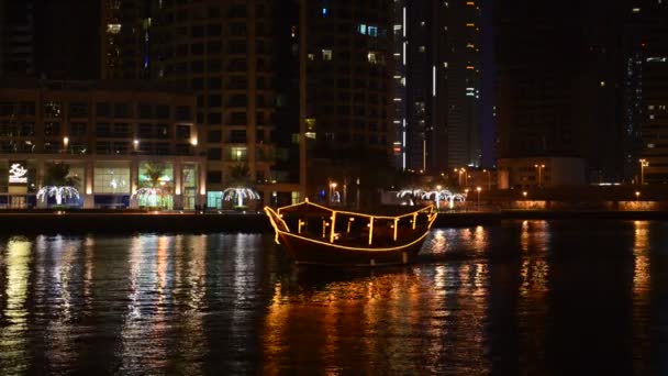 Die nächtliche beleuchtung von dubai marina und dhow boat. Es handelt sich um eine künstliche Kanalstadt, die entlang eines 3 km langen Küstenstreifens am Persischen Golf erbaut wurde. dubai, uae — Stockvideo