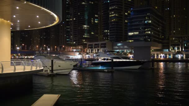 L'illumination nocturne de Dubai Marina et des yachts de luxe. C'est une ville de canaux artificiels, construite le long d'un tronçon de trois kilomètres (3 km) du littoral du golfe Persique. Dubai, Émirats arabes unis — Video