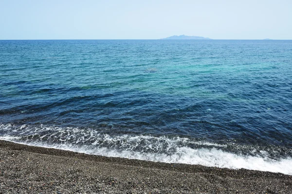 Na plaży z czarnych kamieni wulkanicznych na wyspie santorini, Grecja — Zdjęcie stockowe