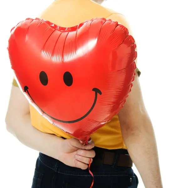 Joven sosteniendo un globo rojo en forma de corazón — Foto de Stock