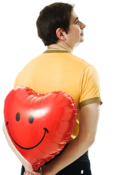 Jovem segurando um balão em forma de coração vermelho — Fotografia de Stock