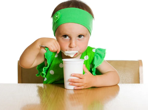 Mädchen isst mit einem Löffel Milchprodukt. — Stockfoto