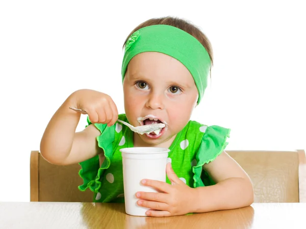 Fille mange avec une cuillère de produits laitiers . — Photo