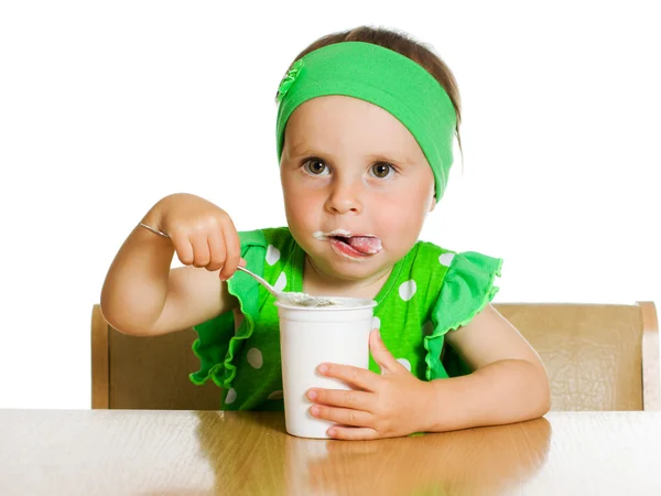 Meisje eet met een lepel zuivelproduct. — Stockfoto