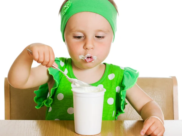 Mädchen isst mit einem Löffel Milchprodukt. — Stockfoto