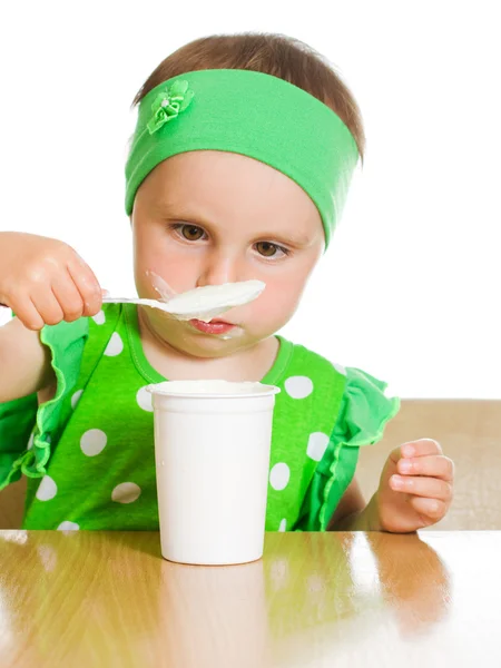 Meisje eet met een lepel zuivelproduct. — Stockfoto