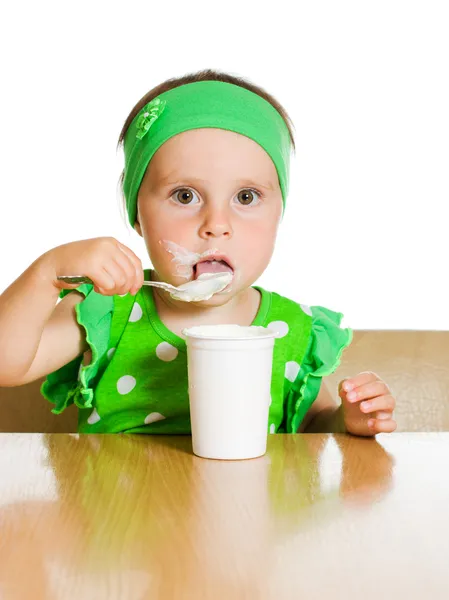 Κορίτσι τρώει με ένα κουτάλι γαλακτοκομικά προϊόν. — Φωτογραφία Αρχείου
