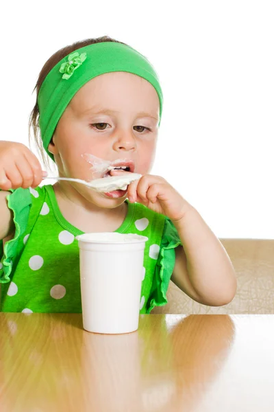 Meisje eet met een lepel zuivelproduct. — Stockfoto