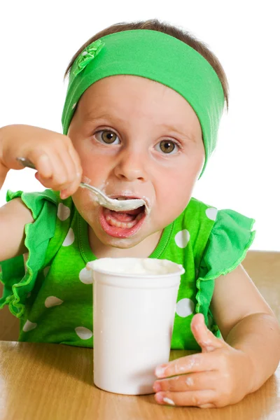 Chica come con una cuchara de productos lácteos . — Foto de Stock