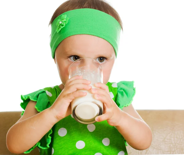 Cute little girl drinking milk from big glass — Stock Photo, Image