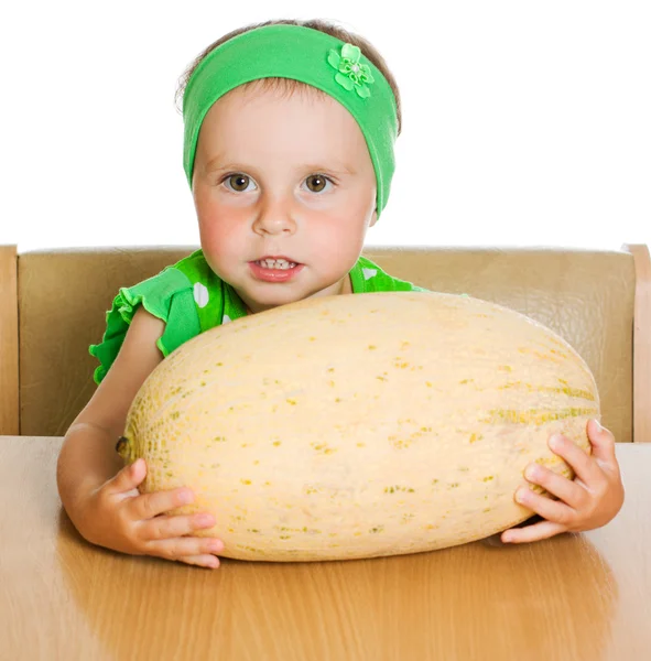 Little girl sitting at a table with a big melon — Stock Photo, Image