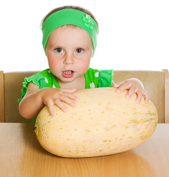 Little girl sitting at a table with a big melon — Stock Photo, Image