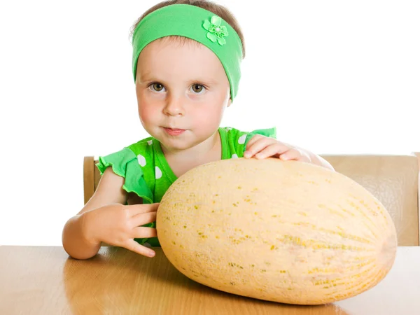 Menina sentada em uma mesa com um grande melão — Fotografia de Stock