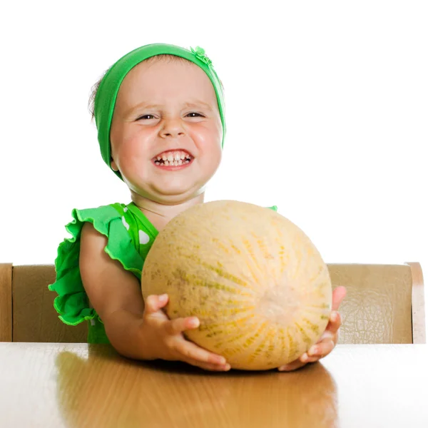 Little girl sitting at a table with a big melon — Stock Photo, Image