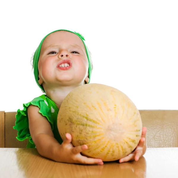 Little girl sitting at a table with a big melon — Stock Photo, Image