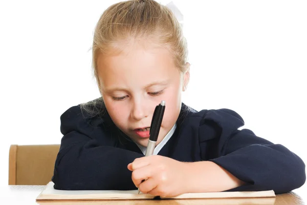 Schoolmeisje schrijft aan een tafel — Stockfoto