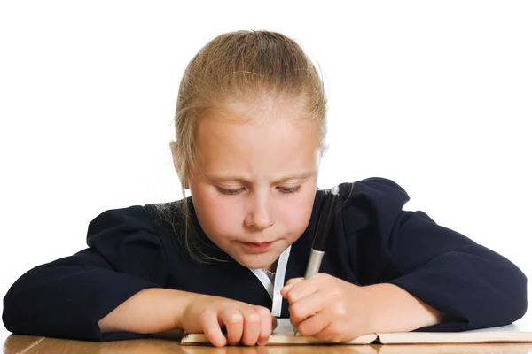 Schoolmeisje schrijft aan een tafel — Stockfoto