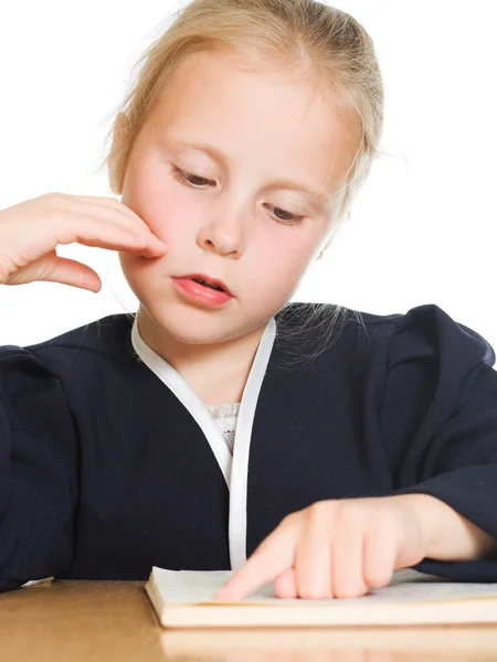 Schoolgirl was reading a book at a table — Stock Photo, Image