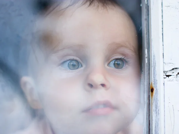 Jeune bébé regardant par la fenêtre — Photo