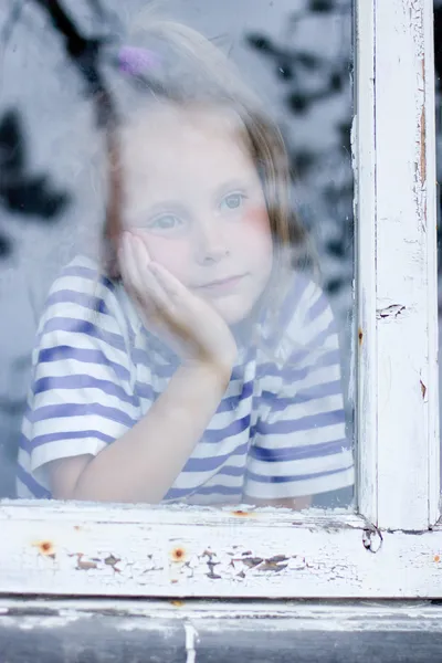 Молодая девушка, выглядывающая из окна — стоковое фото