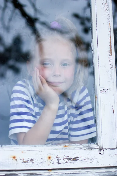 Giovane ragazza guardando dalla finestra — Foto Stock