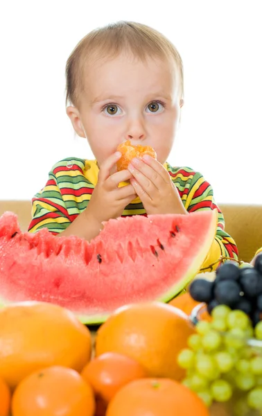 Baby äter frukt på en vit bakgrund — Stockfoto