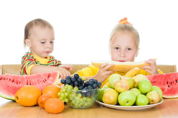 Duas crianças comem o fruto em uma mesa — Fotografia de Stock