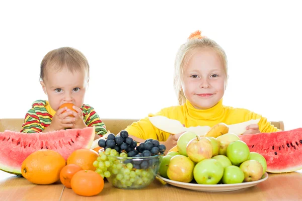 Dos niños comen fruta en una mesa — Foto de Stock