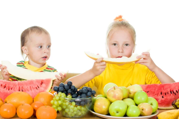 Duas crianças comem o fruto em uma mesa — Fotografia de Stock