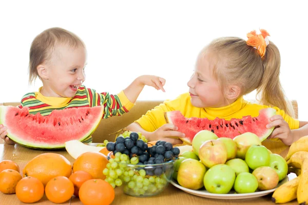 Двоє дітей їдять фрукти за столом — стокове фото