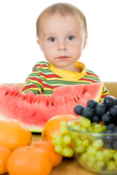 Bebê come frutas em um fundo branco — Fotografia de Stock