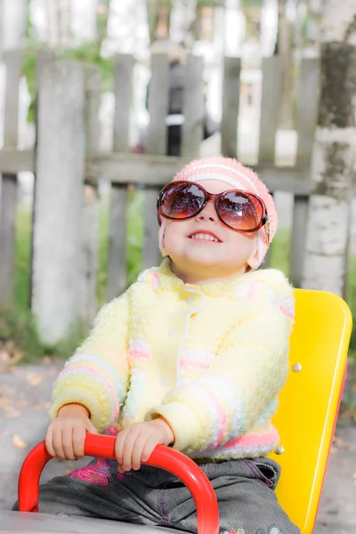 Kid wearing sunglasses on swing — Stock Photo, Image