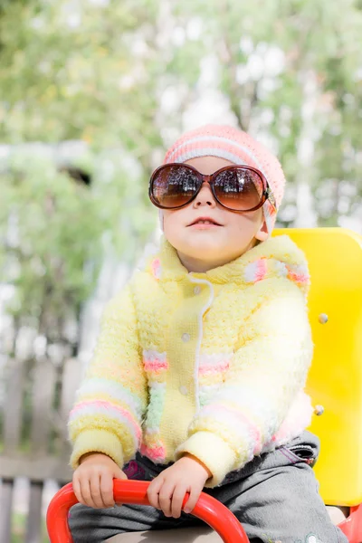 Kid wearing sunglasses on swing — Stock Photo, Image