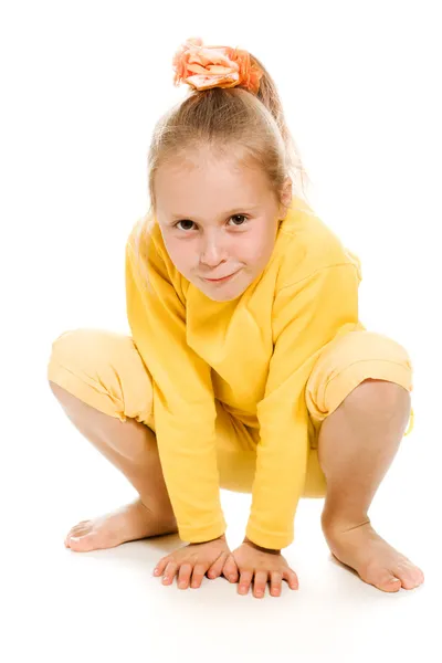 Aranyos lány egy sárga, mosolyogva ül a földön — Stock Fotó