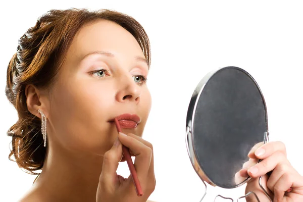 Mujer joven aplicando lápiz labial mirando al espejo —  Fotos de Stock