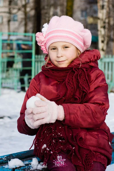 Ung flicka håller ut sin hand i en snöboll — Stockfoto