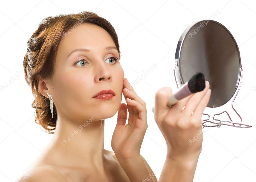 Beautiful woman with looks at his face in a mirror