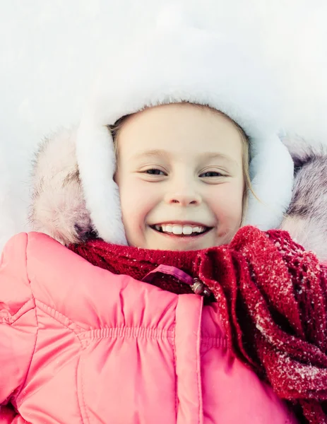 Hermosa chica feliz tumbada en la nieve — Foto de Stock