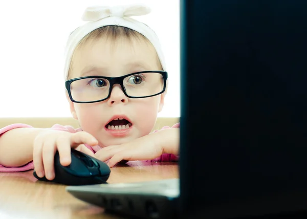 Niedliches Baby mit Brille schaut in den Laptop — Stockfoto