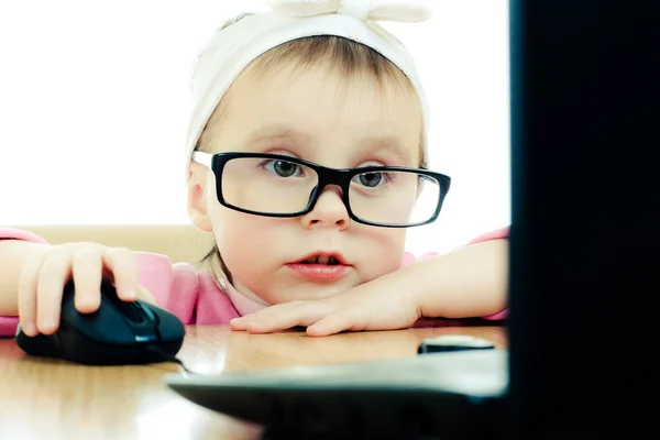 Niedliches Baby mit Brille schaut in den Laptop — Stockfoto