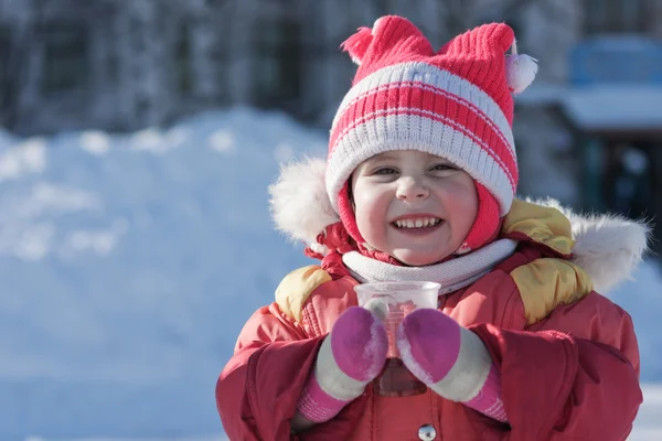 Un petit enfant boit une boisson chaude en hiver — Photo