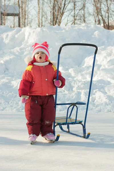Gelukkig kind schaatsen en rodelen in winter buiten — Stockfoto