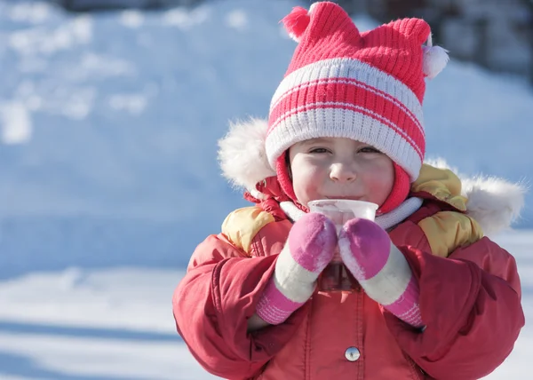 Un petit enfant boit une boisson chaude en hiver — Photo